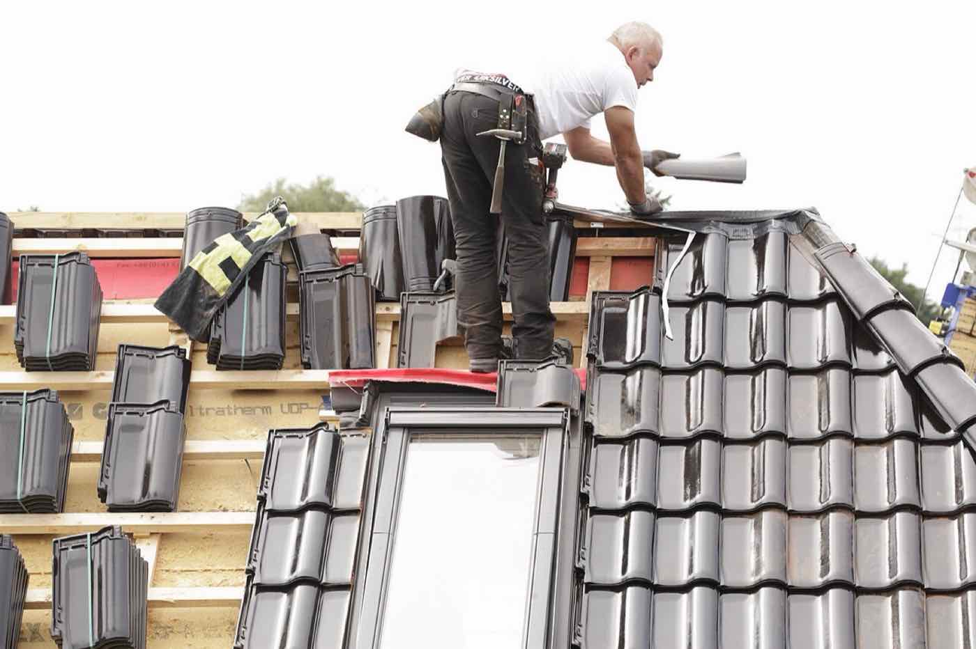 Couvreur au travail sur un faîtage de toiture en tuiles